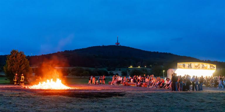 Sonnenwendfeuer und Besucher vor der Dünsberg-Kulisse